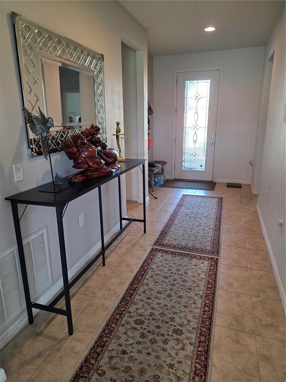 A tiled entryway features a console table, a decorative mirror, and two runner rugs — 576 CANTABRIA DRIVE, DAVENPORT, FL