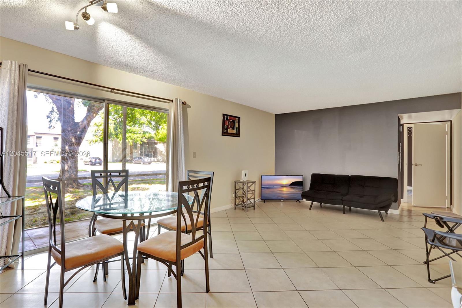 A dining area with a glass table and a living space with a black sofa — 470 N Laurel Dr # 1A, Margate FL 33063, MARGATE, FL