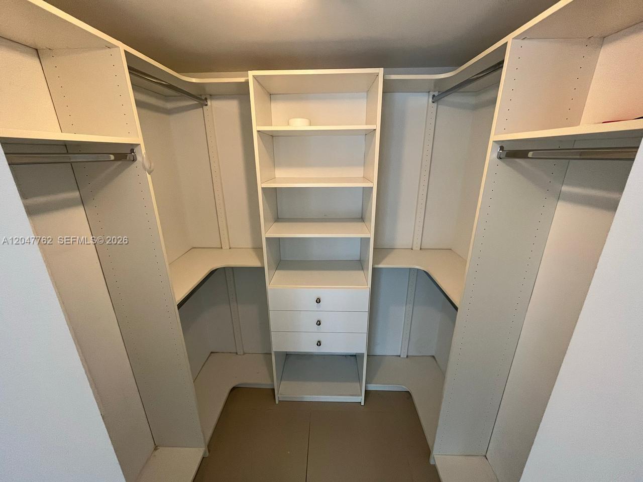 A walk-in closet features white shelving, hanging rods, and a central unit with three drawers — 31 SE 6th St # 1004, Miami FL 33131, MIAMI, FL