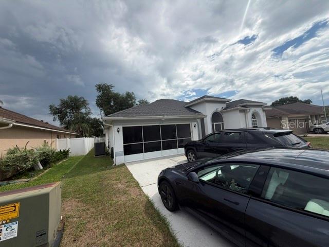 A single-story house with a screened-in garage and two cars parked in the driveway — 6213 ASHFIELD PLACE, WESLEY CHAPEL, FL