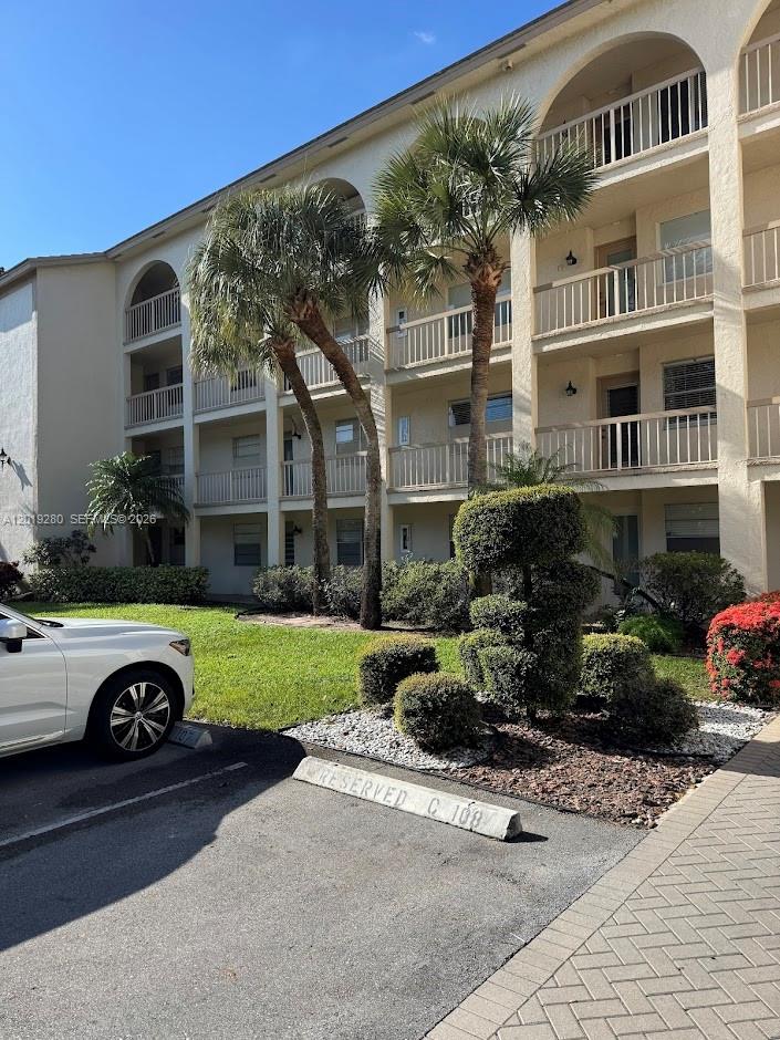 A multi-story apartment building with balconies, palm trees, and a reserved parking space — 4602 Martinique Way # A2, Coconut Creek FL 33066, COCONUT CREEK, FL