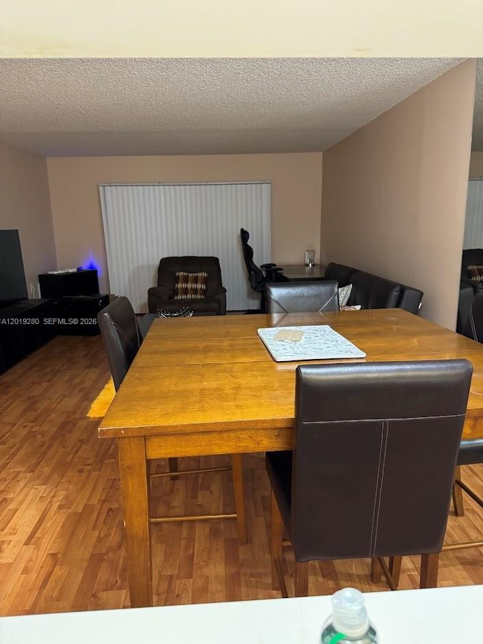 A dining area with a wooden table and chairs sits in front of a living space — 4602 Martinique Way # A2, Coconut Creek FL 33066, COCONUT CREEK, FL