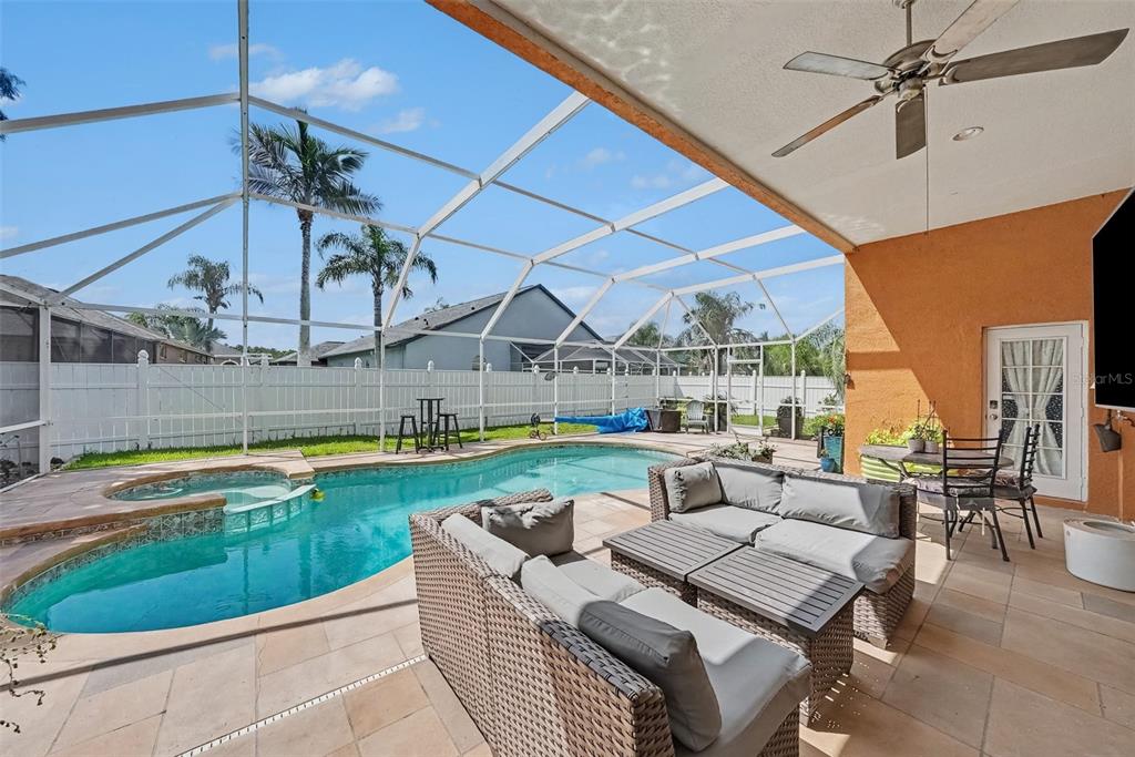 A screened-in patio features a swimming pool, hot tub, and outdoor seating area — 18425 EASTWYCK DR, TAMPA, FL