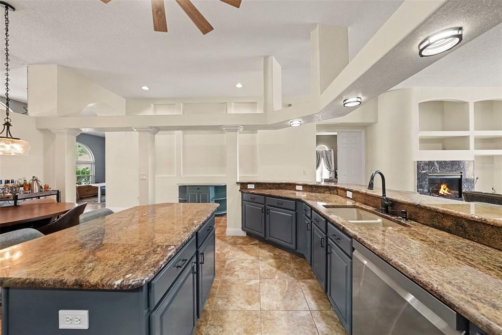 A kitchen with dark gray cabinets, granite countertops, a center island, and tile flooring — 18425 EASTWYCK DR, TAMPA, FL
