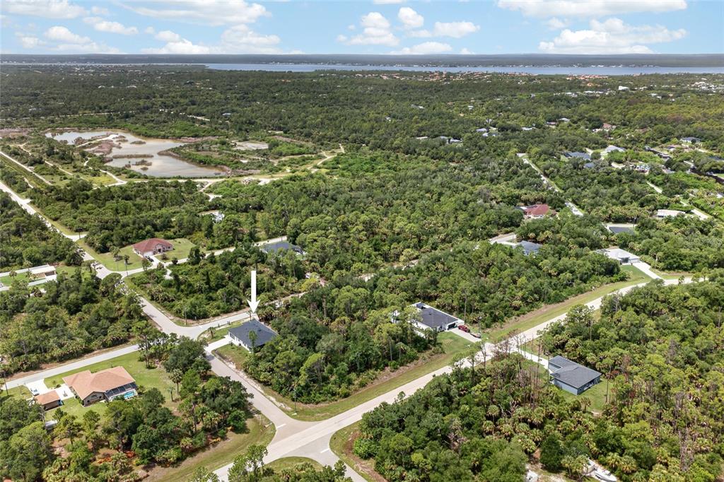 An aerial view shows a single-story house surrounded by dense trees and nearby roads — 1177 COMMERCE STREET, PORT CHARLOTTE, FL