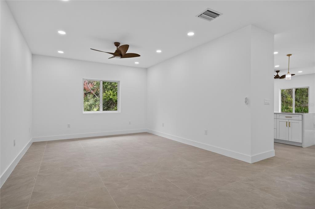 A bright, empty room with light tile flooring, recessed lighting, and a ceiling fan — 1177 COMMERCE STREET, PORT CHARLOTTE, FL