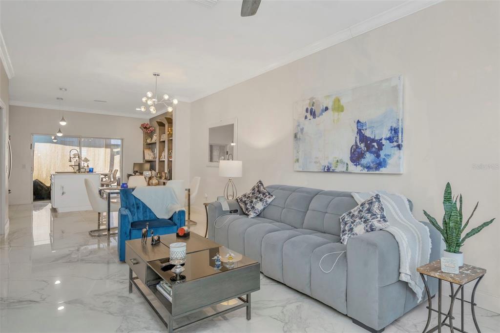 A living room features a blue sofa, a dark coffee table, and white marble flooring — 6765 LAKE ROCHESTER LANE, GIBSONTON, FL