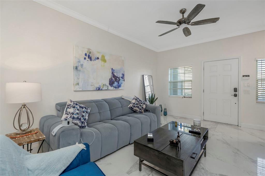 A living room features a grey sofa, a coffee table, and a wood-paneled accent wall — 6765 LAKE ROCHESTER LANE, GIBSONTON, FL