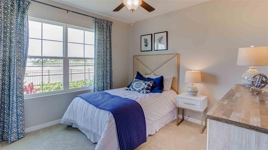 A bedroom features a bed with blue accents, a nightstand, and a window overlooking water — 10840 QUAIL GROVE WAY, SAN ANTONIO, FL
