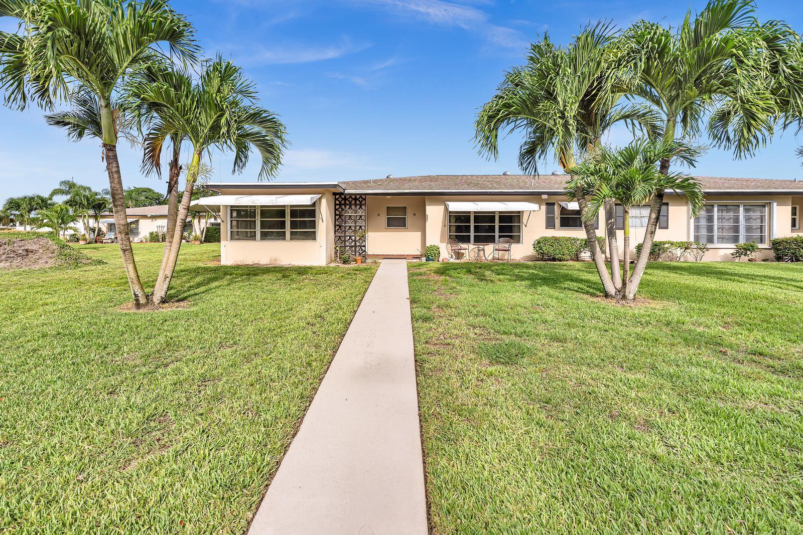 A single-story duplex with a concrete walkway leading to the front entrance and palm trees — 840 N High Point Blvd Boulevard N # B, Delray Beach FL 33445, DELRAY BEACH, FL
