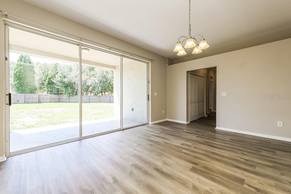 A room with wood-look flooring, a sliding glass door, and a chandelier — 6707 CAMBRIDGE PARK DRIVE, APOLLO BEACH, FL
