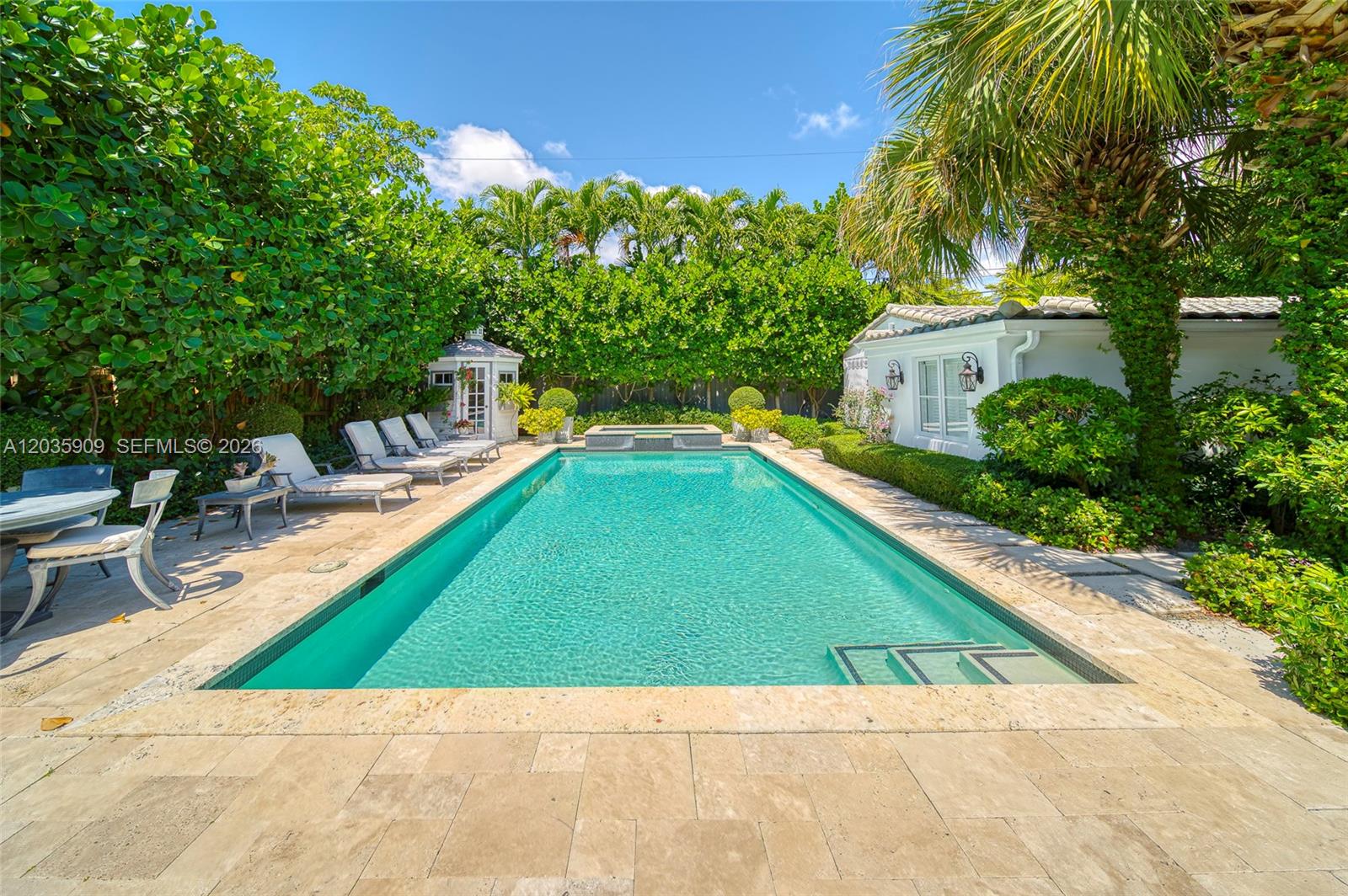 A rectangular swimming pool is surrounded by a stone patio, lounge chairs, and lush landscaping — 2534 Flamingo Dr, Miami Beach FL 33140, MIAMI BEACH, FL