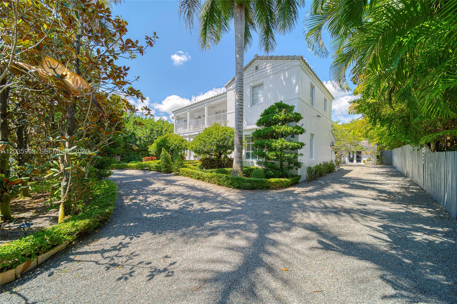A white two-story house with a gravel driveway and palm trees under a blue sky — 2534 Flamingo Dr, Miami Beach FL 33140, MIAMI BEACH, FL