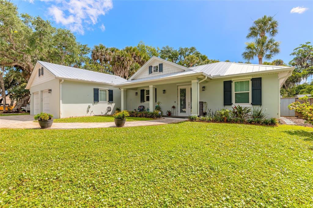 A light green single-story house with a metal roof and a large front lawn — 1107 S ORANGE STREET, NEW SMYRNA BEACH, FL