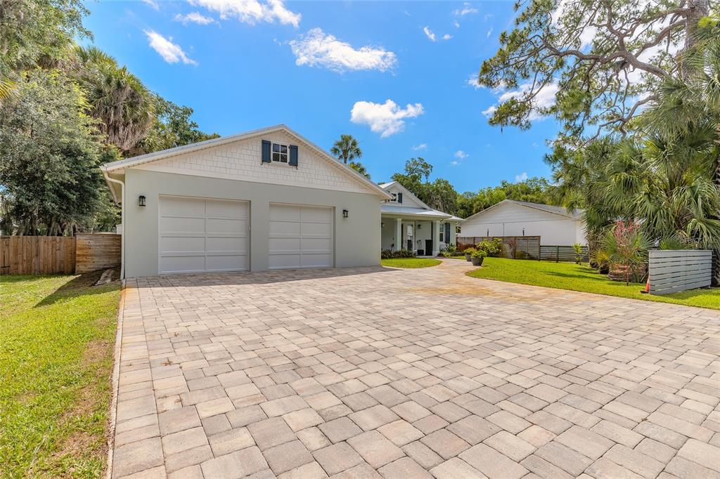 A paved driveway leads to a two-car garage attached to a single-story residential home — 1107 S ORANGE STREET, NEW SMYRNA BEACH, FL