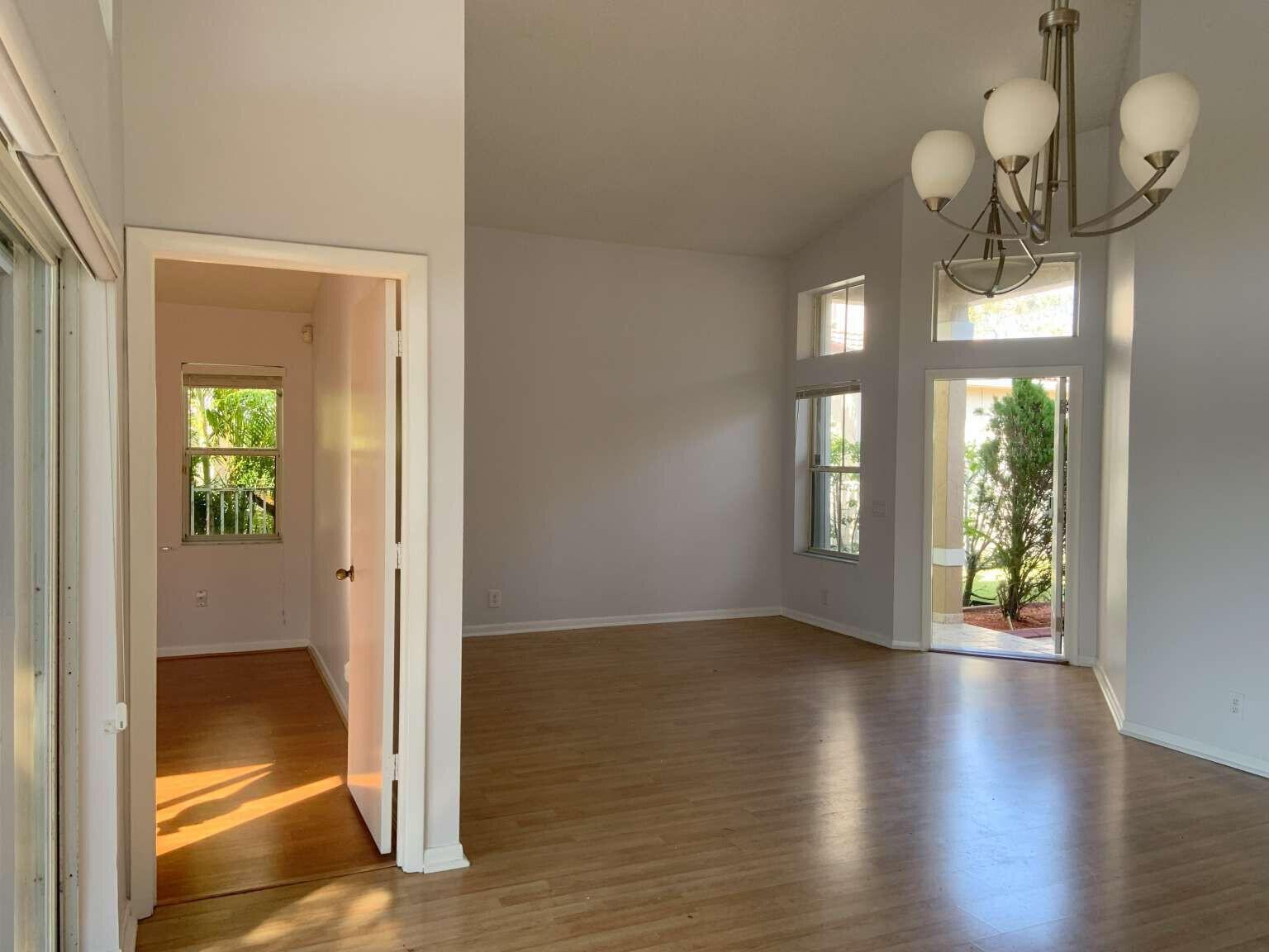 A bright living area with wood-look flooring, a chandelier, and a doorway to another room — 856 Stanton Drive, Weston FL 33326, WESTON, FL