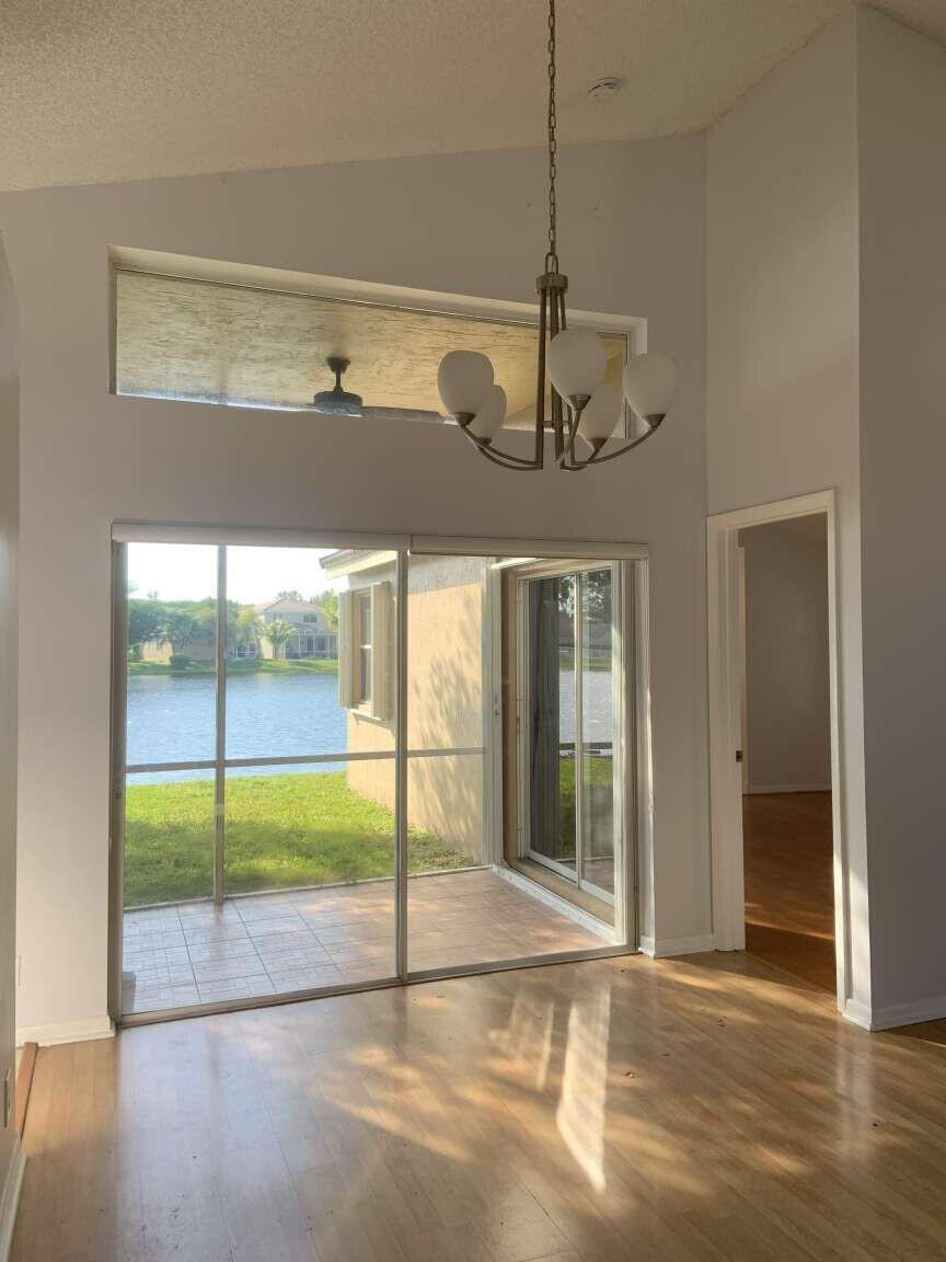A dining area with wood floors, a chandelier, and sliding doors opening to a lake view — 856 Stanton Drive, Weston FL 33326, WESTON, FL