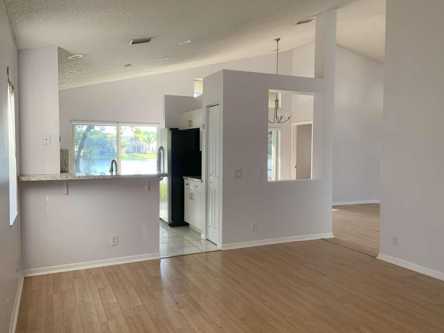 A kitchen with a breakfast bar, white cabinets, and a view of a lake outside — 856 Stanton Drive, Weston FL 33326, WESTON, FL