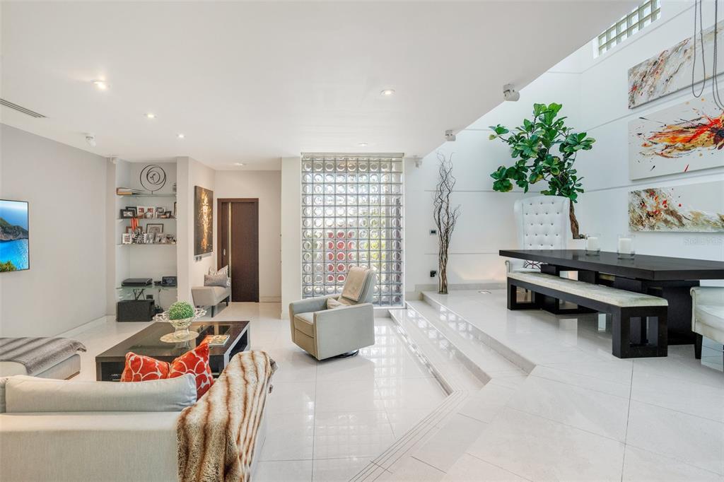A modern living and dining area features white tile floors, a glass block wall, and furniture — 2008 ESPAÑA STREET, SAN JUAN, PR