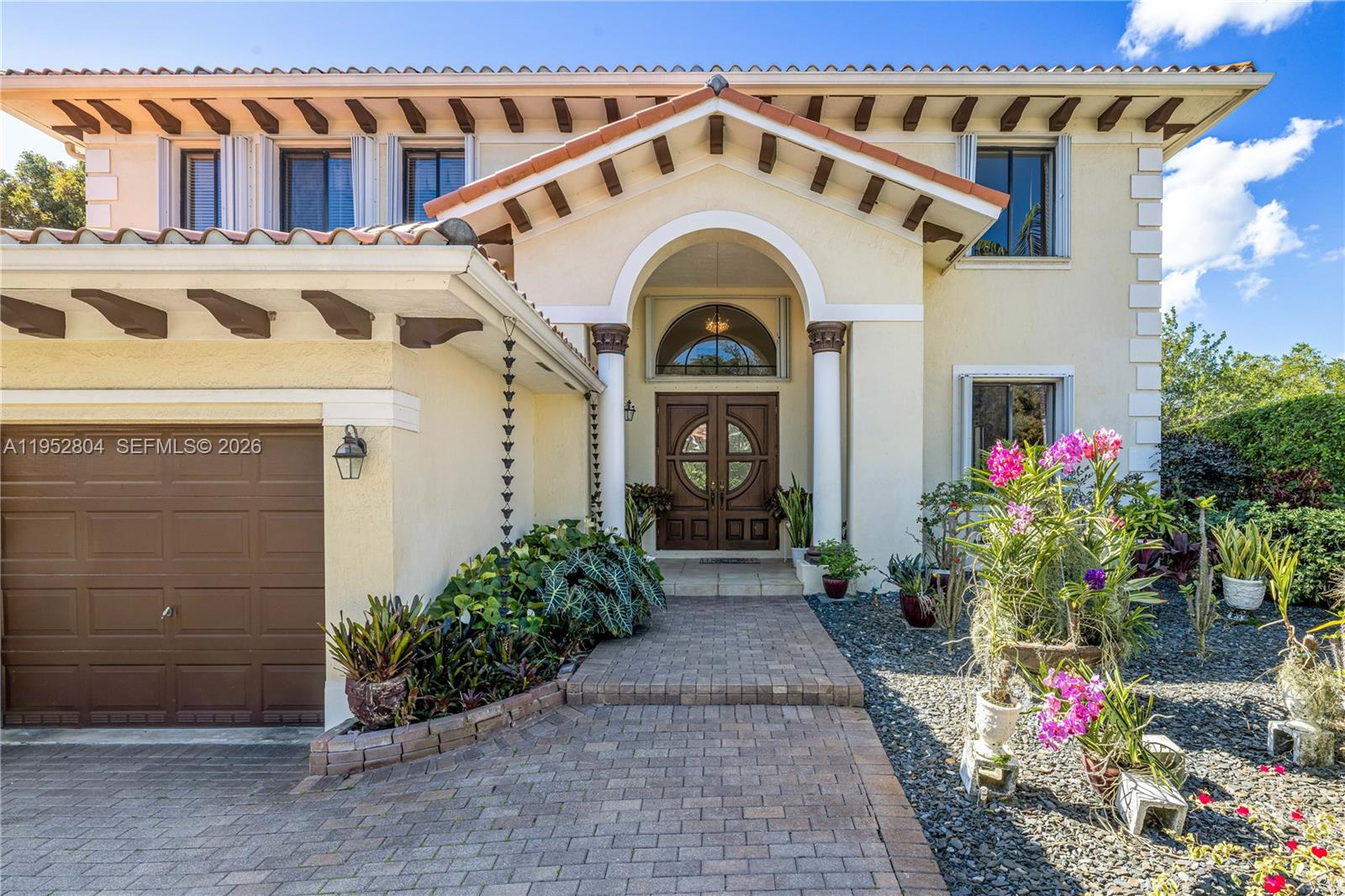 The exterior of a two-story house features a tiled roof, arched entryway, and brick driveway — 19086 SW 76th Ave, Cutler Bay FL 33157, CUTLER BAY, FL