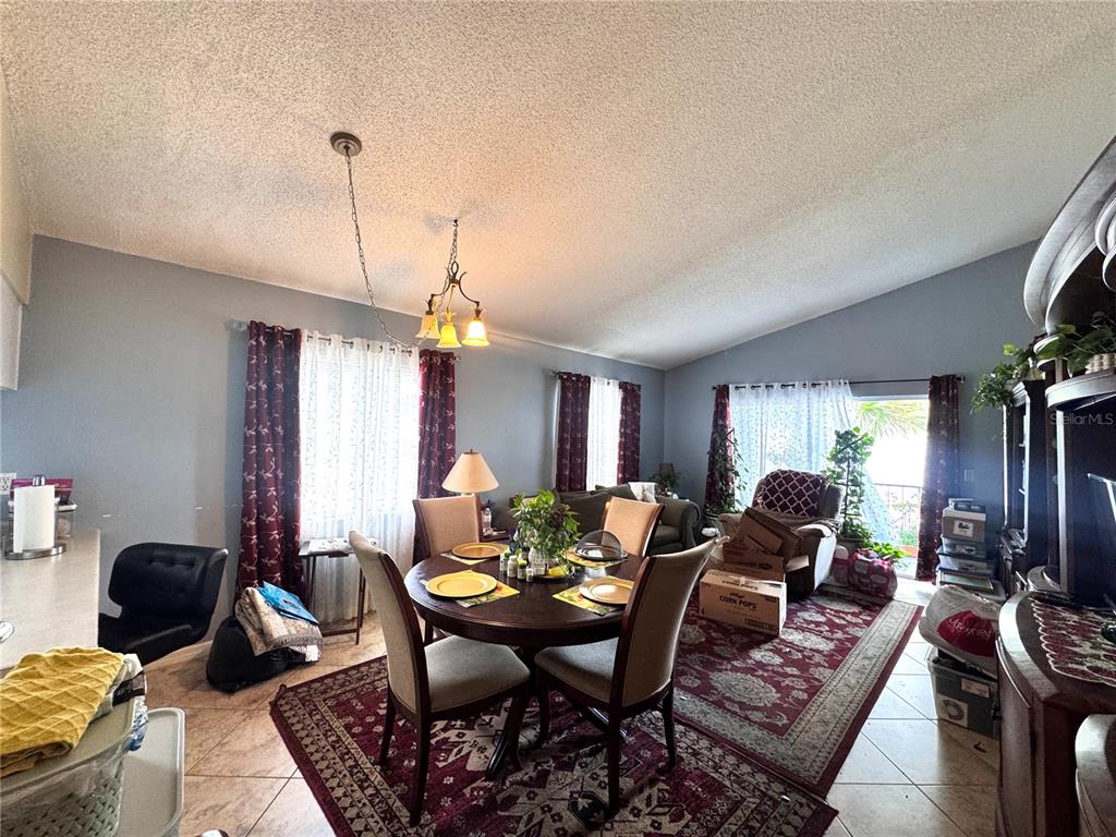 A dining area features a round wooden table, chairs, and a rug on tiled floors — 6008 AMBERLY AVENUE UNIT F63, ORLANDO, FL