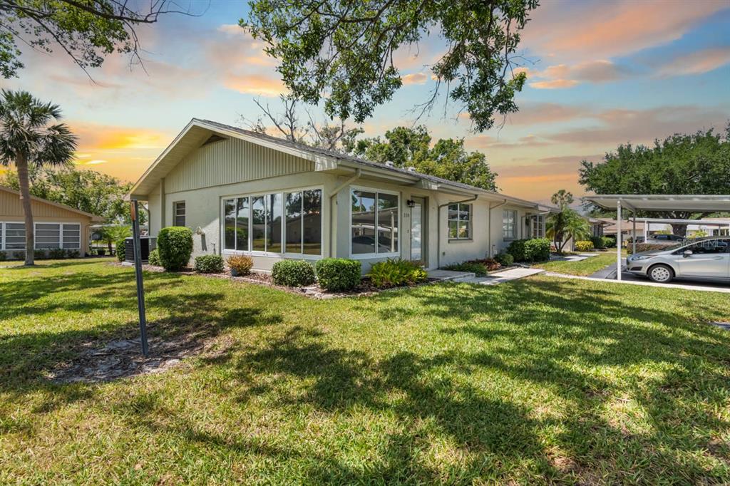 A single-story house with a light-colored exterior, large windows, and an attached carport — 330 GLOUCESTER BOULEVARD, SUN CITY CENTER, FL