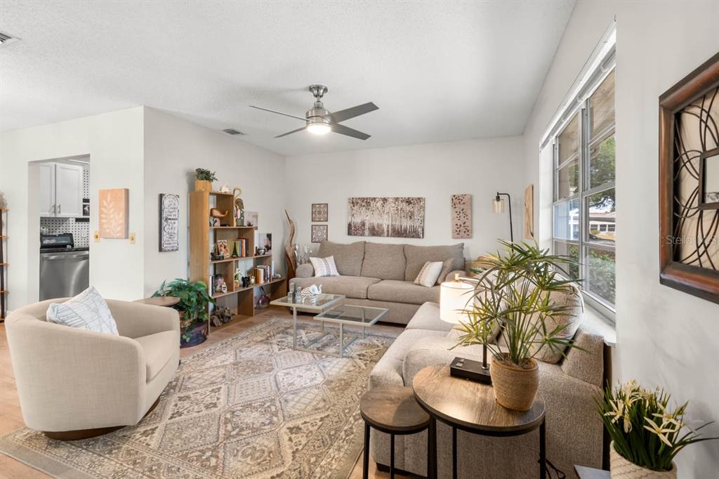 A living room features a beige sofa, a cream armchair, and a patterned area rug — 330 GLOUCESTER BOULEVARD, SUN CITY CENTER, FL