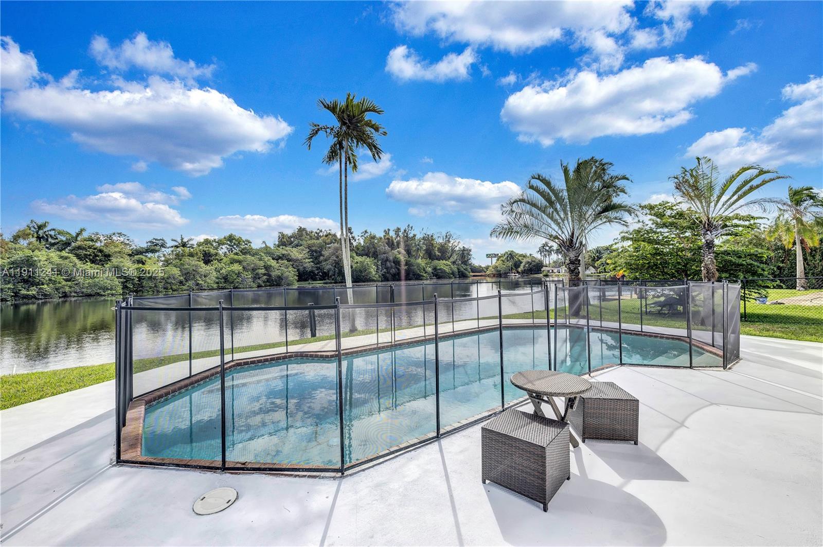 A swimming pool with a safety fence sits on a patio overlooking a lake — 217 N 31st Ave, Hollywood FL 33021, HOLLYWOOD, FL