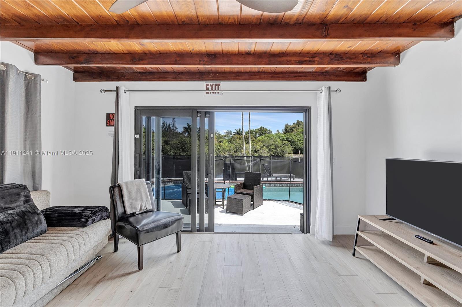 A living room with wood-beamed ceilings and sliding glass doors opening to a pool patio — 217 N 31st Ave, Hollywood FL 33021, HOLLYWOOD, FL