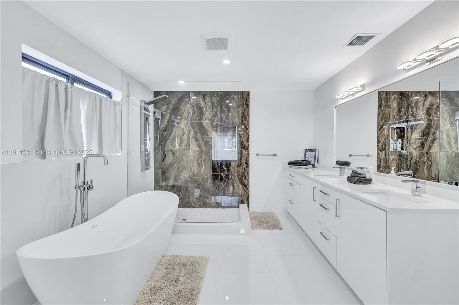 A modern bathroom features a freestanding tub, a glass-enclosed shower, and a double vanity — 217 N 31st Ave, Hollywood FL 33021, HOLLYWOOD, FL