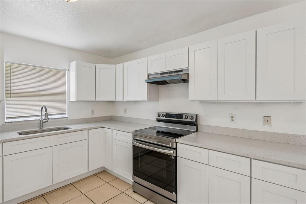 A kitchen features white cabinets, stainless steel appliances, and light-colored countertops — 3808 N WHITTIER STREET, TAMPA, FL