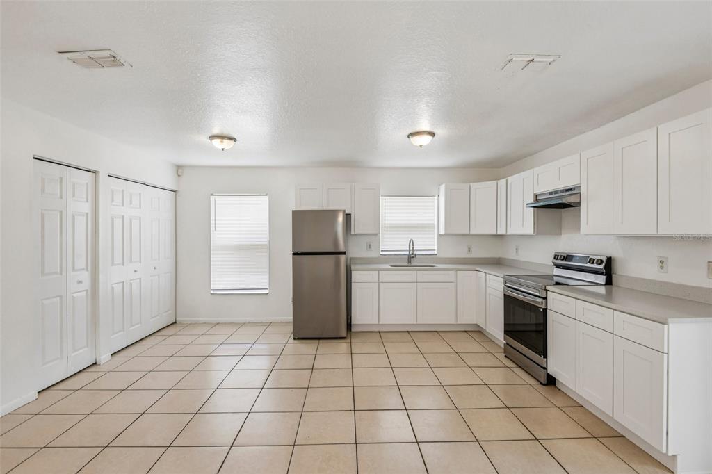 A kitchen features white cabinets, stainless steel appliances, and light-colored tile flooring — 3808 N WHITTIER STREET, TAMPA, FL