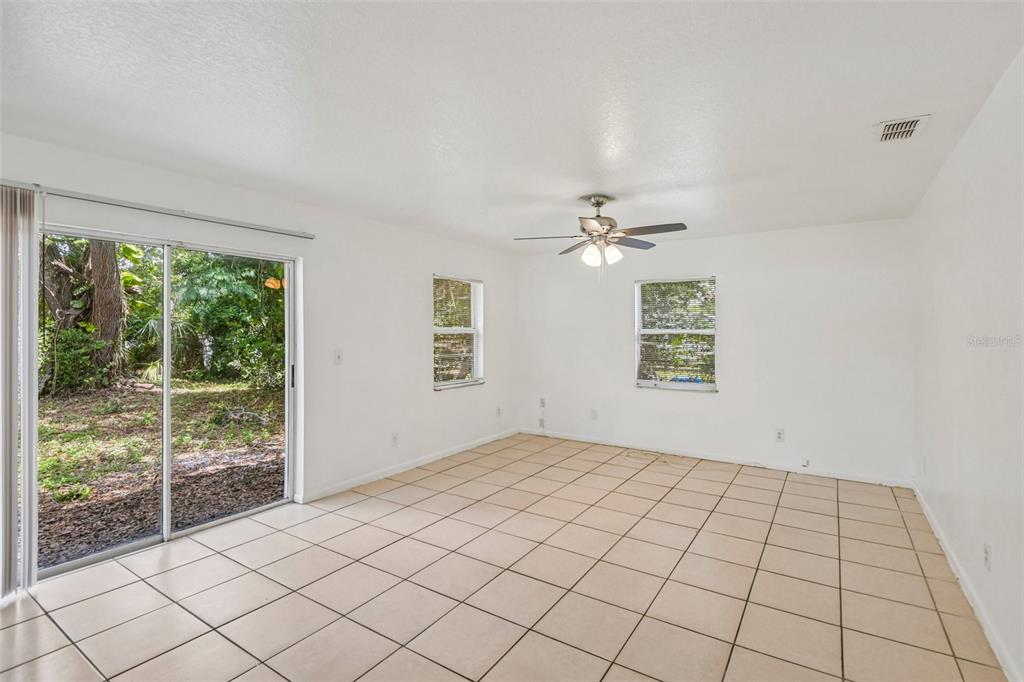 An empty room with white walls, beige tile flooring, a ceiling fan, and sliding glass doors — 3808 N WHITTIER STREET, TAMPA, FL