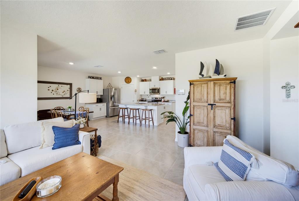 An open-concept living room flows into a kitchen with a central island and white cabinetry — 3432 ISLEWOOD COURT, OCOEE, FL