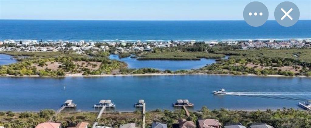 An aerial view shows a waterway with boat docks, coastal vegetation, and the ocean beyond — 36 N RIVERWALK DRIVE, PALM COAST, FL