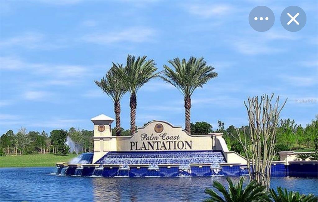 The entrance sign for Palm Coast Plantation features a tiered water fountain in a lake — 36 N RIVERWALK DRIVE, PALM COAST, FL