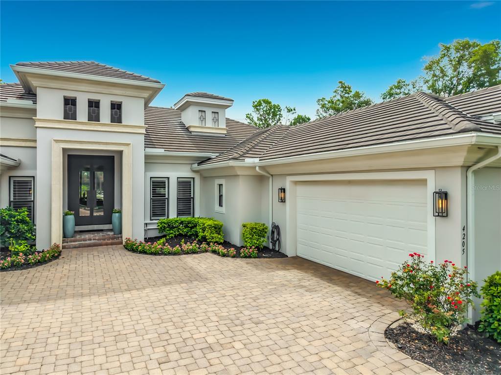 A modern house exterior features a paver driveway, a white garage door, and a dark entryway — 4205 CLARICE ESTATES DRIVE, WINDERMERE, FL
