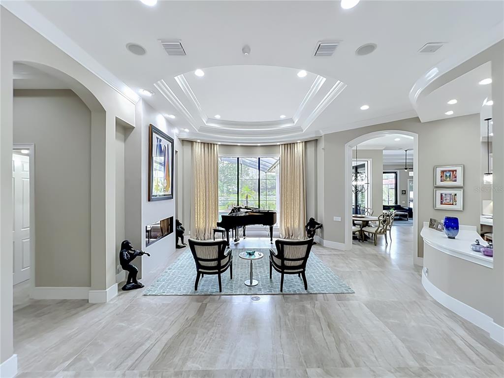 A spacious living room features a grand piano, a fireplace, and a tray ceiling — 4205 CLARICE ESTATES DRIVE, WINDERMERE, FL