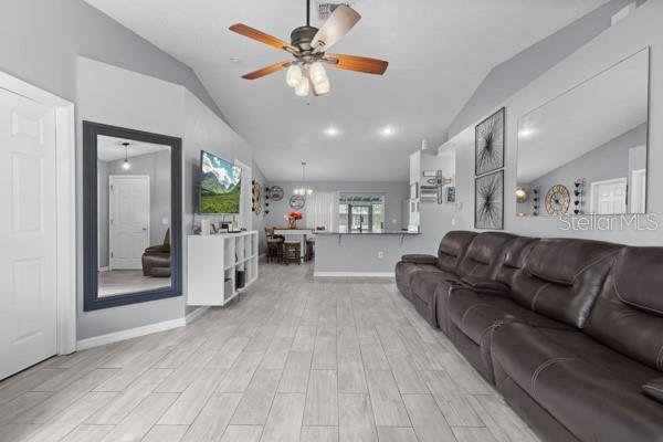 A living room features a dark leather sectional, light wood-look tile flooring, and a ceiling fan — 2472 PINE CHASE CIRCLE, ST CLOUD, FL