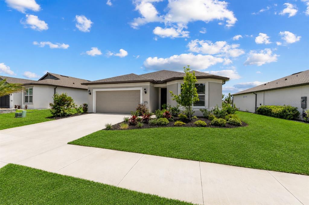 A single-story suburban house features a two-car garage, gray siding, and a landscaped front yard — 8394 SW 52ND LANE ROAD, OCALA, FL