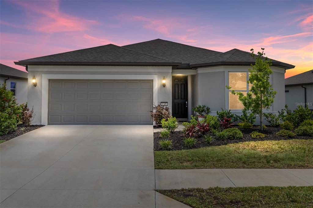 A single-story house with a gray garage, dark front door, and landscaped front yard — 8394 SW 52ND LANE ROAD, OCALA, FL