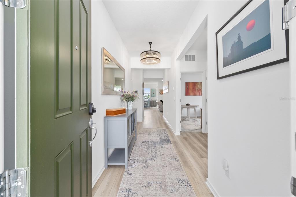 A view from an open green door into a bright hallway with light wood flooring — 8394 SW 52ND LANE ROAD, OCALA, FL