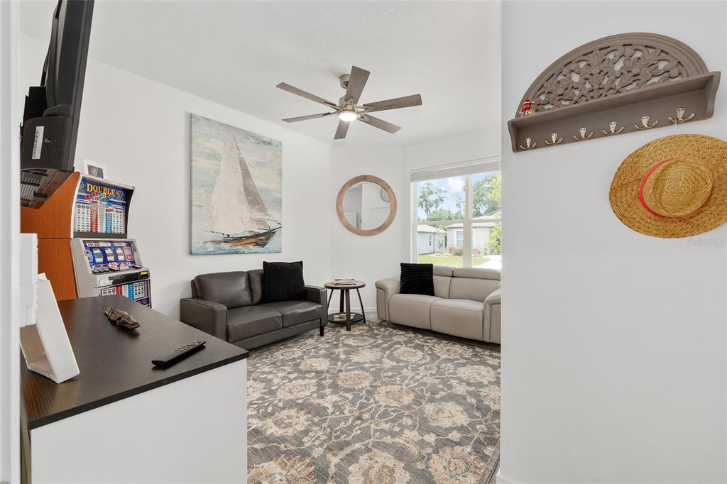 A living room features two sofas, a patterned area rug, and a slot machine — 8394 SW 52ND LANE ROAD, OCALA, FL