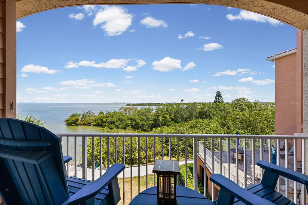 A balcony with two blue chairs overlooks a body of water and lush green trees — 5000 CULBREATH KEY WAY UNIT 9-216, TAMPA, FL