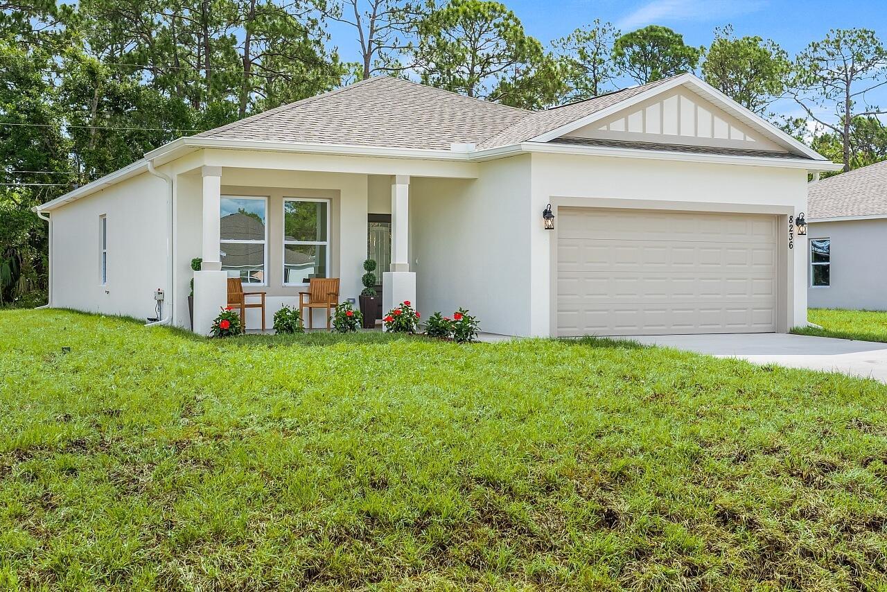 A single-story house with a beige stucco exterior, a two-car garage, and a front porch — 8236 104th Court, Vero Beach FL 32967, VERO BEACH, FL
