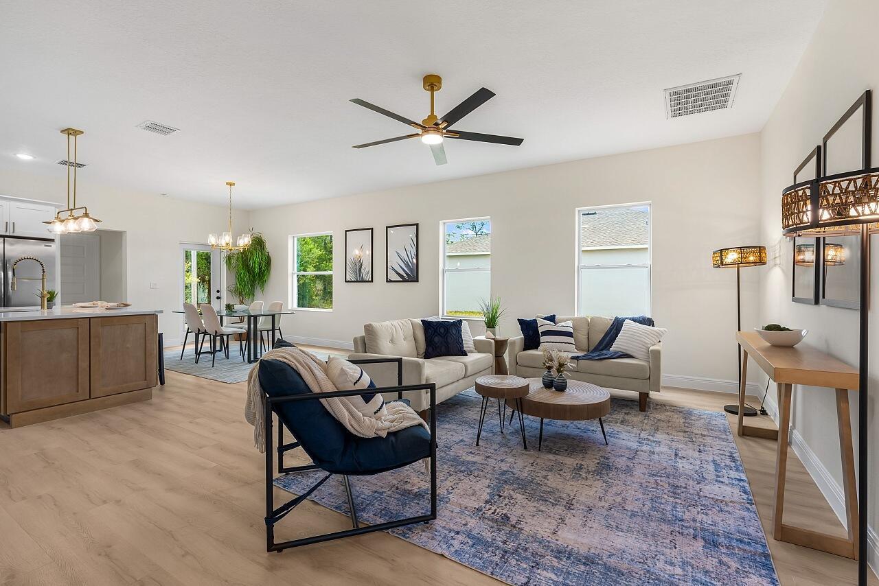 A bright open-concept living and dining area features light wood floors and modern neutral furnishings — 8236 104th Court, Vero Beach FL 32967, VERO BEACH, FL