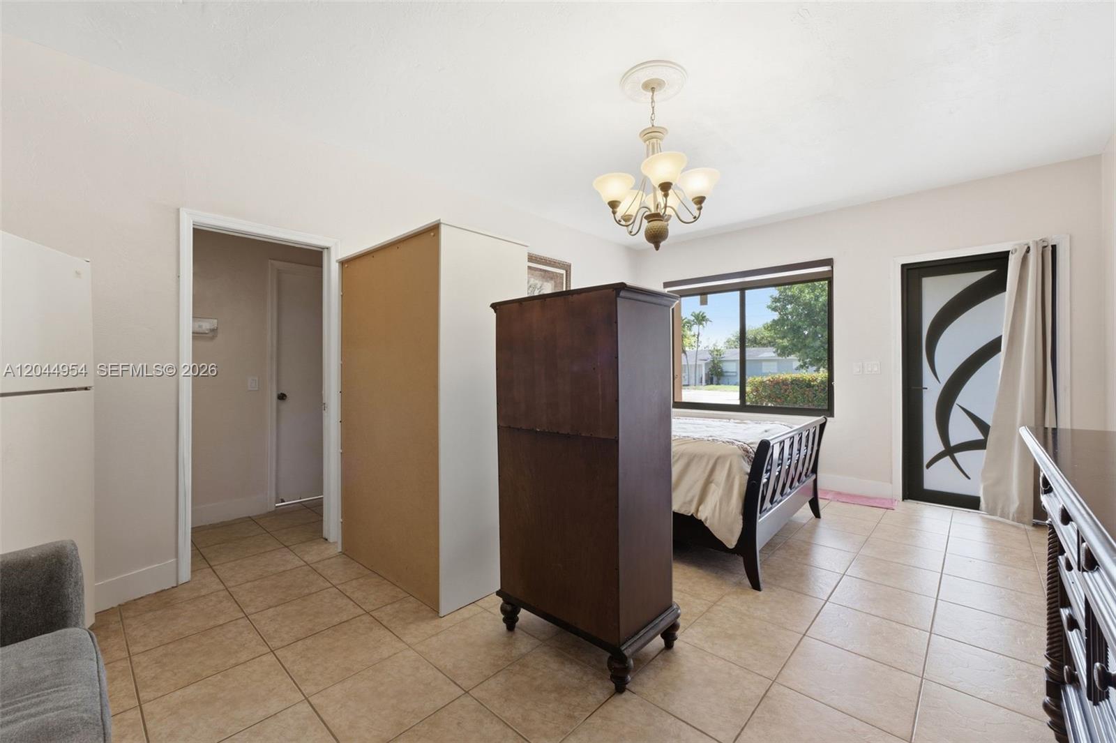 A bedroom features tile flooring, a dark wood armoire, a bed, and a glass door — 1419 SW 76th Ct, Miami FL 33144, MIAMI, FL