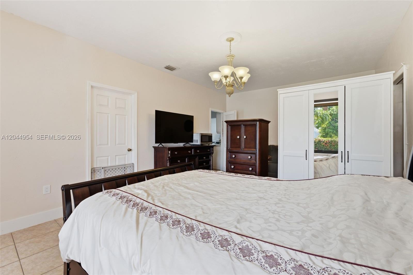 A bedroom features a bed, a dark wood dresser with a television, and a white wardrobe — 1419 SW 76th Ct, Miami FL 33144, MIAMI, FL