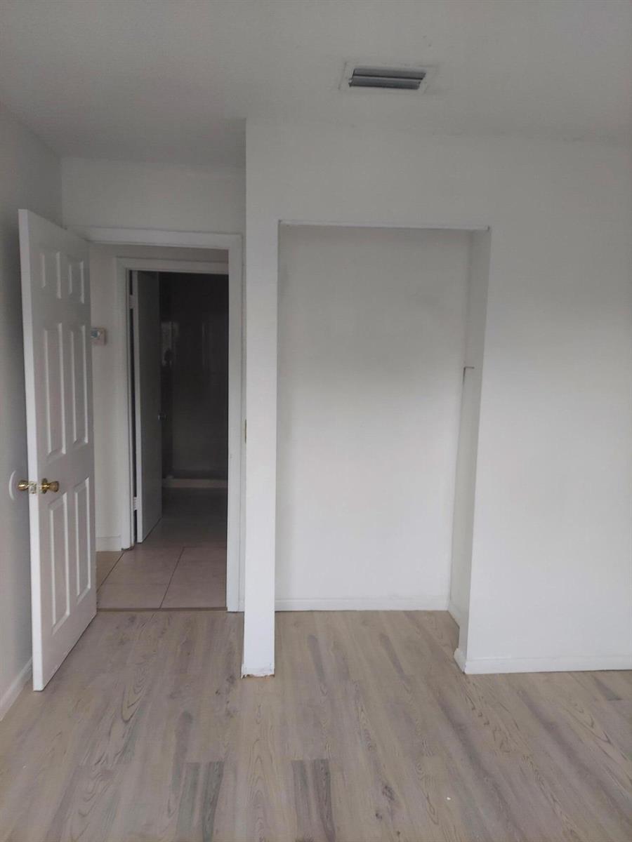 An interior view showing a room with light wood-look flooring and an open closet space — 2215 NW 56th Avenue # e, Lauderhill FL 33313, LAUDERHILL, FL