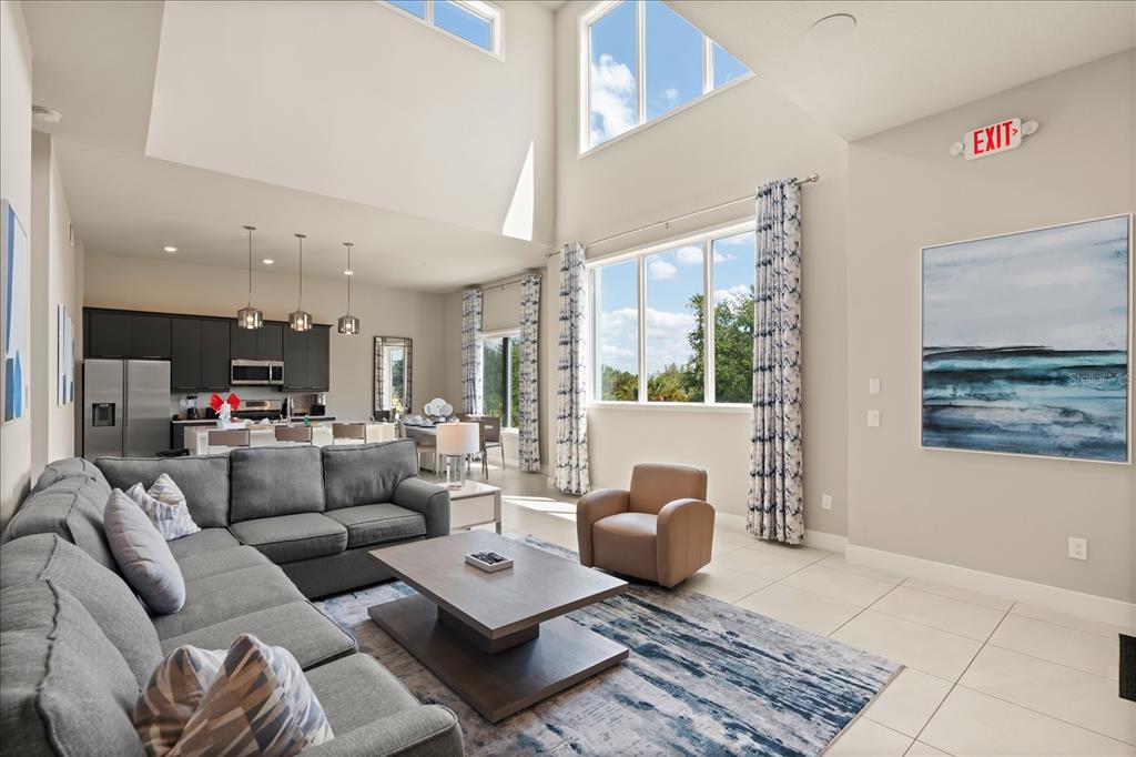 A living room with a gray sectional, coffee table, and high ceilings opens to a kitchen — 7770 SANDY RIDGE DRIVE 218 BLDG 28 With Elevator, KISSIMMEE, FL